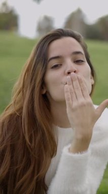 Koyu renk saçlı genç bir kadının kameraya öpücük attığı yakın görüntü - 1080 dikey video