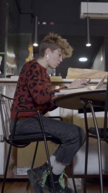 Boş bir restoranda bilgisayar kullanan genç bir kadının zemin görünümü - FullHD dikey video