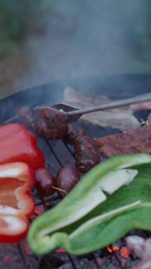 Farklı türde et pişiren tanınmamış bir adam sosisleri çeviriyor - yavaş çekim - FullHD dikey video