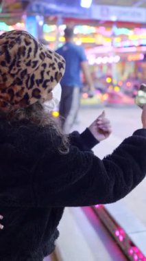 Koruyucu göz yaşartıcı sprey maskeli ve Noel Baba şapkalı bir kadın Valencia lunaparkının önünde yürüyordu.