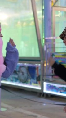Happy Girls 'ün Valencia lunaparkında kağıt taş makas oynarken üç kez çizdiği gece ağır çekimde FullHD dikey video.