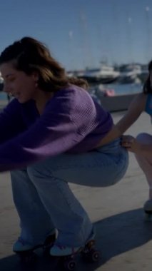 Limanda kuyrukta üç mutlu kız paten kayıyor ve düşüyor, slomo - FullHD dikey video