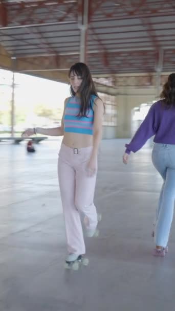 3人の女の子のローラーのスケートの追跡パン屋外 スロモー フルHd垂直ビデオ — ストック動画