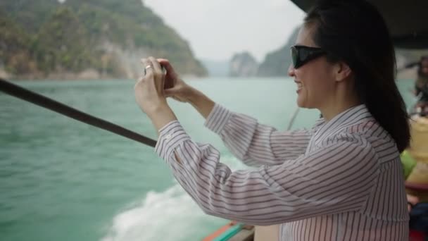 シャツとメガネを着ている女性が湖を撮影します 横4Kビデオ — ストック動画