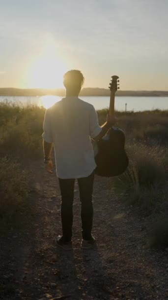 在夕阳下弹奏吉他和拍击腿的轮廓男人 慢镜头 垂直的Fullhd视频 — 图库视频影像