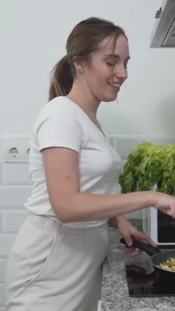 快乐的女孩在厨房烹调蔬菜餐的同时歌唱 垂直发射 — 图库视频影像