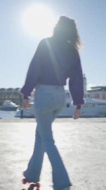 Kız paten kayıyor limanda güneş ışığında, Slomo arkadan - FullHD dikey video