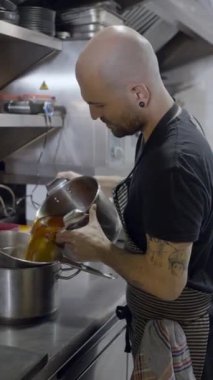Restorandaki erkek aşçının tenceredeki süzme sosu, FullHD dikey video.