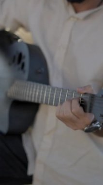 Kırsal kesimde gitar çalan İspanyol sakallı hippi. Geri çekil, yavaş çekim. Dikey FullHD video.