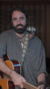 Erkek müzisyen kameraya yaklaşıyor gitar çalmak için gülümsüyor.