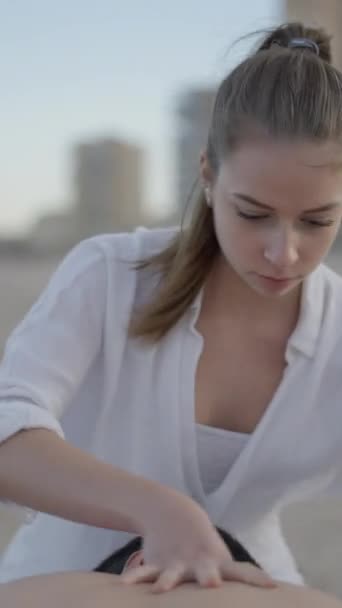 海岸で若い男性にマッサージをするプロのマッサージセラピスト 白人女性マッサージャー フルHd垂直ビデオ — ストック動画