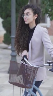 Plaza 'da bisikletle yürüyen genç bir kadının yavaş hareketi. - Dikey