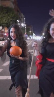 Boş bir yolda yürüyen iki güzel kız Cadılar Bayramı kostümü giyiyorlar - orta ölçekli - dikey 1080