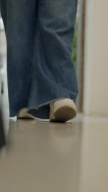 Kameranın objektifine doğru yürüyen beyaz snickers ve kotlu kadın bacakları - Dikey FullHD video