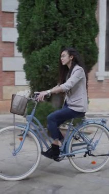 Sıradan giyinen Faslı bir kadın, gündüz vakti bisiklete biniyor. İzleme - Dikey
