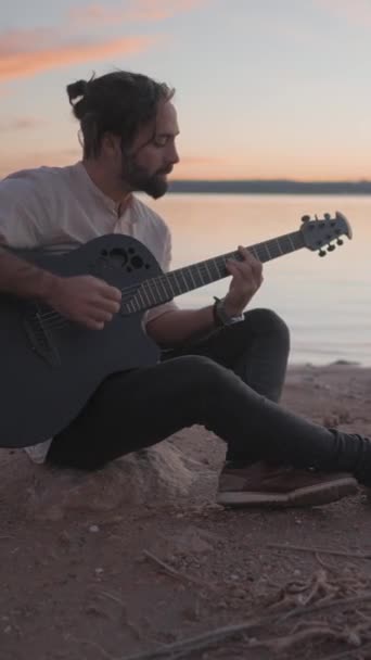 西班牙阿利坎特的Torrevieja Pink湖畔 一名年轻男子在海滩上弹奏吉他手和弦的轮廓 垂直Fullhd视频 — 图库视频影像