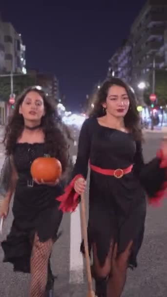 Girls Witch Costumes Walking Road Holding Pumpkin Broomsticks Wide Shot — Stock Video