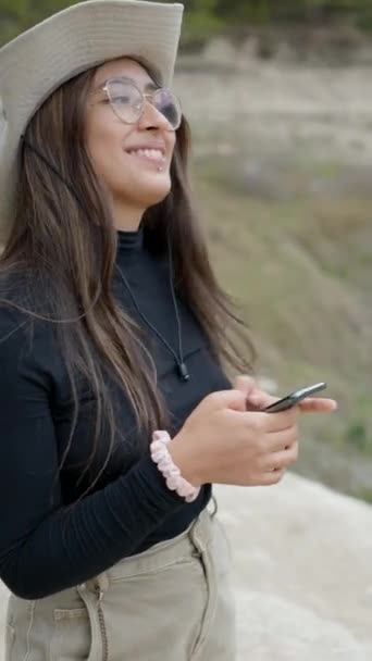 Dziewczyna Kapeluszu Wykorzystuje Telefon Uśmiecha Się Kamery Kamienistym Krajobrazie Blisko — Wideo stockowe
