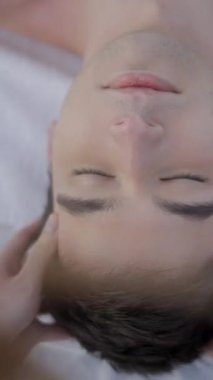 Omuz hizasında, genç oğlanın kafasına masaj yapan bir kadın. Oğlan masaj sırasında rahat - FullHD dikey video