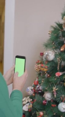 Yaşlı kadın süslenmiş Noel ağacının videosunu çekiyor. Orta Çekim - Dikey FullHD video