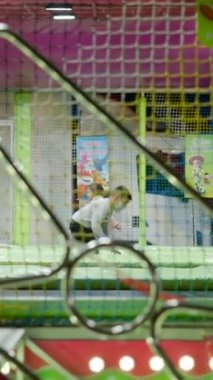 İspanya 'daki bir covid-19 salgını sırasında Valencia lunaparkının trambolin çekimine atlayan maskeli çocuklar - FullHD dikey video
