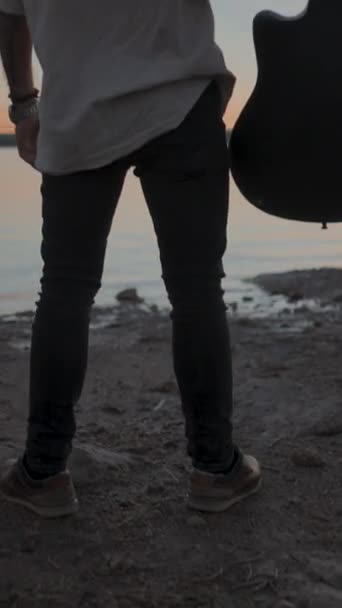 Mężczyzna Stojący Nad Brzegiem Jeziora Podnoszący Gitarę Powietrzu Wspaniałym Złotym — Wideo stockowe