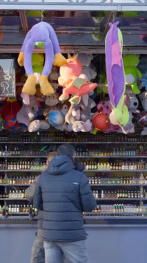 Koruyucu maskeli iki yetişkin adam Valencia Country Funfair 'deki atış poligonunda şişe vuruyor.