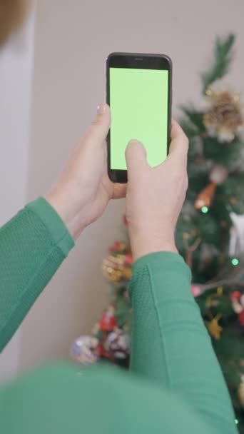 緑のスクリーンが付いている携帯電話が付いているクリスマスの木の写真を取る古いスペインの女性 クローズアップ 垂直フルHdビデオ — ストック動画