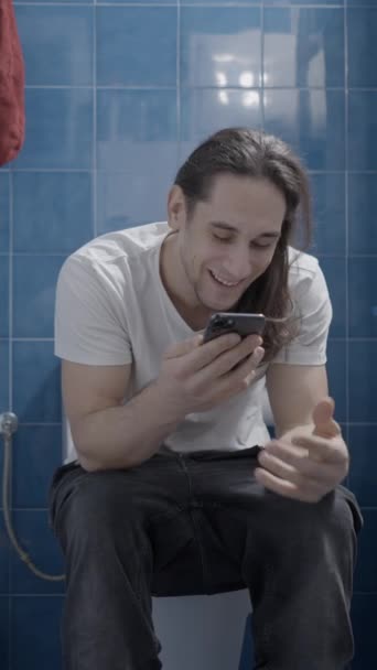 年轻的高加索人在浴室里用他的手机发送音频讯息 前沿射击 垂直视频 — 图库视频影像