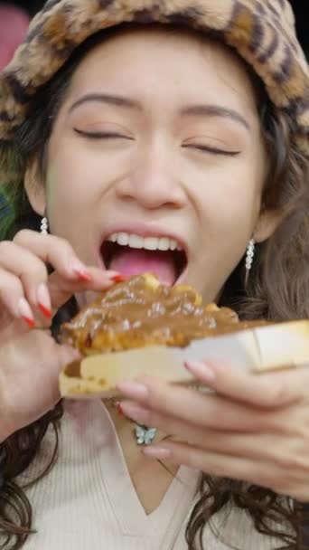 在瓦伦西亚游乐场 快乐女人在晚上面对特写镜头时吃着带有巧克力的华夫饼 Fullhd垂直视频 — 图库视频影像