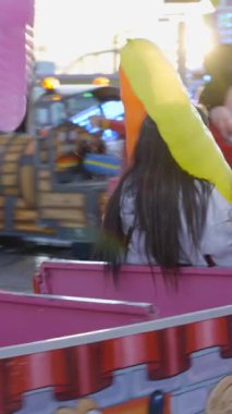 Trenchu chu cazibesi - Valencia 'da bir lunaparkta küçük bir trene binen insanlar. Goofy ve Mickey Mouse kostümlü adamlar FullHD dikey video sürücülerini eğlendiriyor.