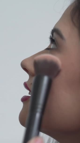 美しいコロンビアの女性は メイクアップアーティストが彼女の頬にブラッシングを適用しながら 笑顔を見ています クローズアップ サイドビュー 1080 — ストック動画