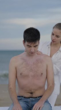 İkili olmayan kişi plajda masaj yaptırır, masaj masasında oturur - orta ekran - FullHD dikey video