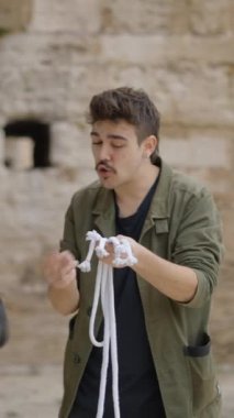 Sihirbazlığın mükemmel ustalığı. Sihirbaz bir iple bir numara gösteriyor. Sihirbaz halatla numara yapıyor. Sihirbaz illüzyonist, ortadan kaybolur ve yükselir. - FullHD dikey video