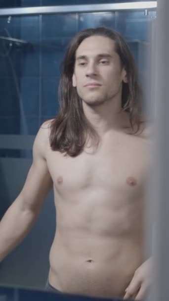 在浴室镜子前脱掉衬衫的年轻人 中镜头 垂直录像 — 图库视频影像