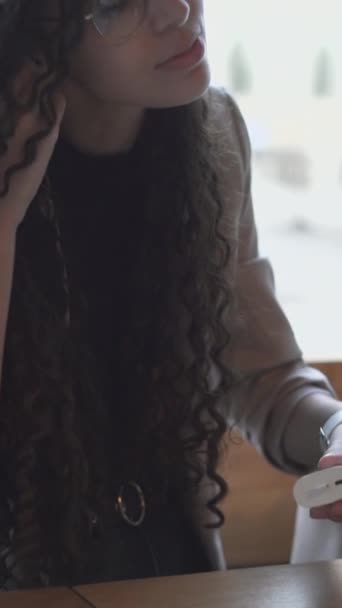 Красива Молода Жінка Окулярах Встановлює Навушники Bluetooth Сидячи Відкритому Повітрі — стокове відео