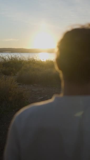 日落时分带着吉他在湖畔跳跃的年轻人侧影 垂直Fullhd视频 — 图库视频影像