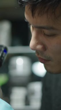 Taylandlı dövme sanatçısı bir müşteriyle dövme makinesi kullanırken - yaratıcı konsept - FHD dikey video