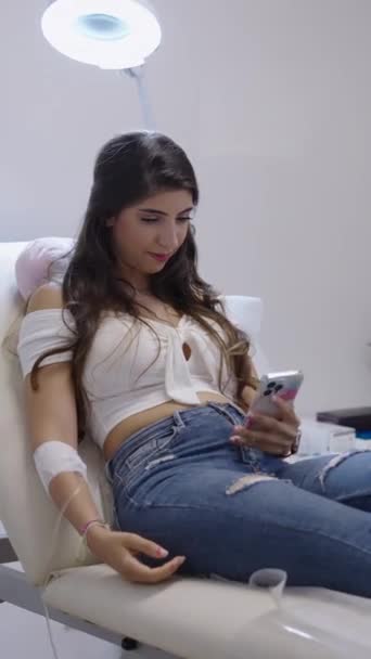 Chica Caucásica Tratamiento Seroterapia Mirando Teléfono Móvil Fhd Vídeo Vertical — Vídeos de Stock