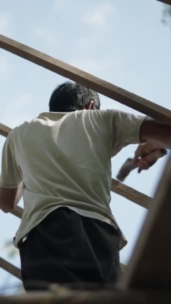 屋根の木に釘をピンするためにハンマーを使用するアジアの男 Fhd 垂直ビデオ Fhd 垂直ビデオ — ストック動画