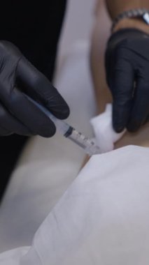 Doktor mezoterapi hastalarının bacağına iğne enjekte ediyor. FHD dikey sağlık hizmeti.
