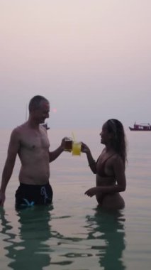 Suda bir çift gün batımında bira içiyor - FHD Dikey