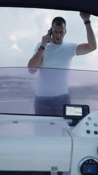 男の子は 彼の友人が電話で話している間にボートを運転します 垂直Fhdラグジュアリーライフスタイル — ストック動画