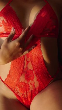Kırmızı iç çamaşırlı bir kadının elini vücudunda gezdirmesi FHD dikey video.