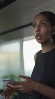 Bangkok 'ta bir apartman dairesinde koşu bandında yürürken telefon eden genç zenci kadın - Yaşam Tarzı Konsepti - FHD Dikey Video