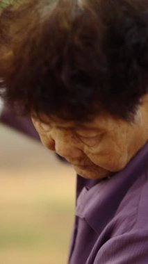 FHD dikey videoyu süpüren yaşlı bir kadının portresi.