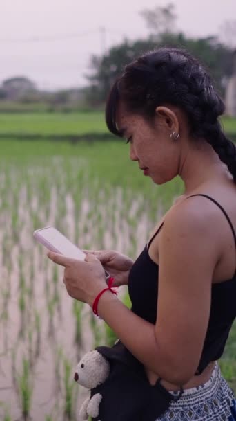 Азиатка Смотрит Свой Телефон Рисовом Поле Fhd Вертикальное Видео — стоковое видео