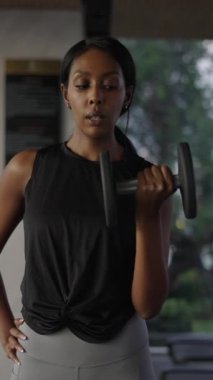 Siyah kadın güçlü bir vücut geliştirici gibi davranıyor ve spor salonunda gülüyor - yaşam tarzı konsepti - FHD dikey video
