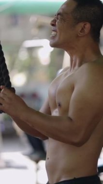 Asyalı güçlü adam makara ile triseps egzersizi yapıyor - FHD dikey sokak spor salonu