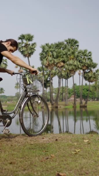 ポニーテールを持つ男の子は湖に自転車に乗って座る Fhd垂直ビデオ — ストック動画